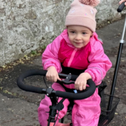 Flickan Caledonia cyklar på sin momo trehjuling.
