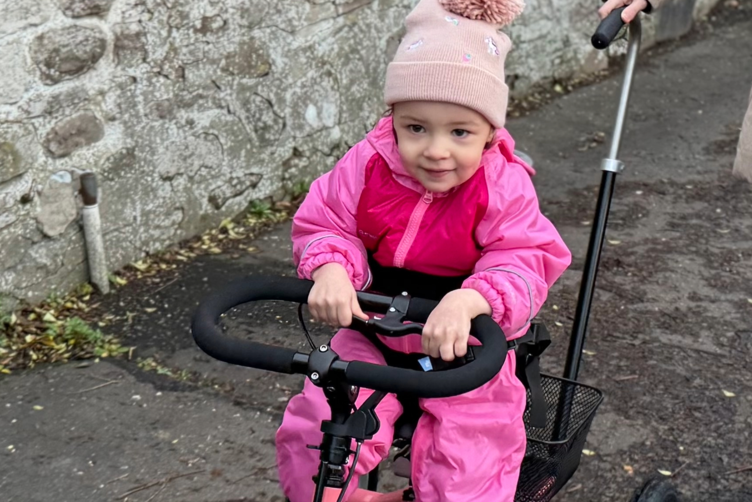 Flickan Caledonia cyklar på sin momo trehjuling.